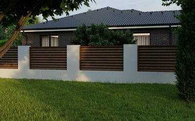 Modern house with a white fence and brown panels, surrounded by greenery.